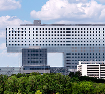 Image of a large, multi-story hospital on a sunny day.
